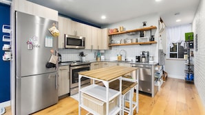A modern kitchen with stainless steel appliances, wooden cabinets, and a central island with seating.