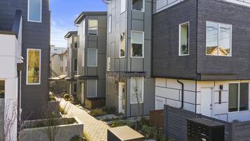A modern multi-story residential building with a narrow pathway between the units.