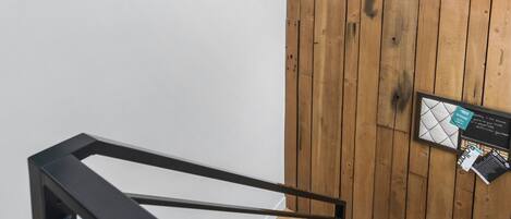 Une pièce moderne avec un mur en bois, un escalier en métal noir et un luminaire original.