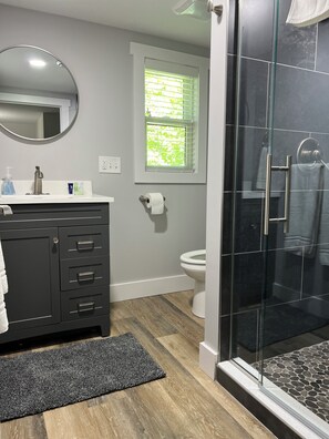 Un baño moderno con ducha, inodoro y tocador.