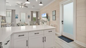 Una cocina moderna con armarios blancos, una isla grande e iluminación colgante.