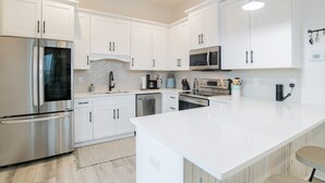 Una cocina moderna con armarios blancos, electrodomésticos de acero inoxidable y una isla grande.