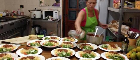 A kitchen with multiple plates of food, a stove, and a refrigerator.