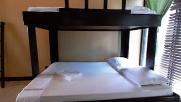 Un lit superposé avec un matelas et des oreillers, une table de chevet et une fenêtre avec des stores.