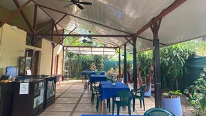 An outdoor covered patio area with tables and chairs, a reception desk, and ceiling fans. - Cabinas Arribadas  (Cuajiniquil)