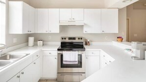 A modern kitchen with white cabinets, a stainless steel oven, and a sink. - Quiet Getaway to Tampa & Orlando (Mulberry)