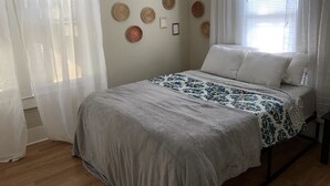 Ein Schlafzimmer mit einem Bett, weißen Vorhängen und Wanddekorationen.