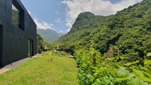 Un bâtiment moderne doté de grandes fenêtres, d’une pelouse bien entretenue et surplombant un paysage montagneux.
