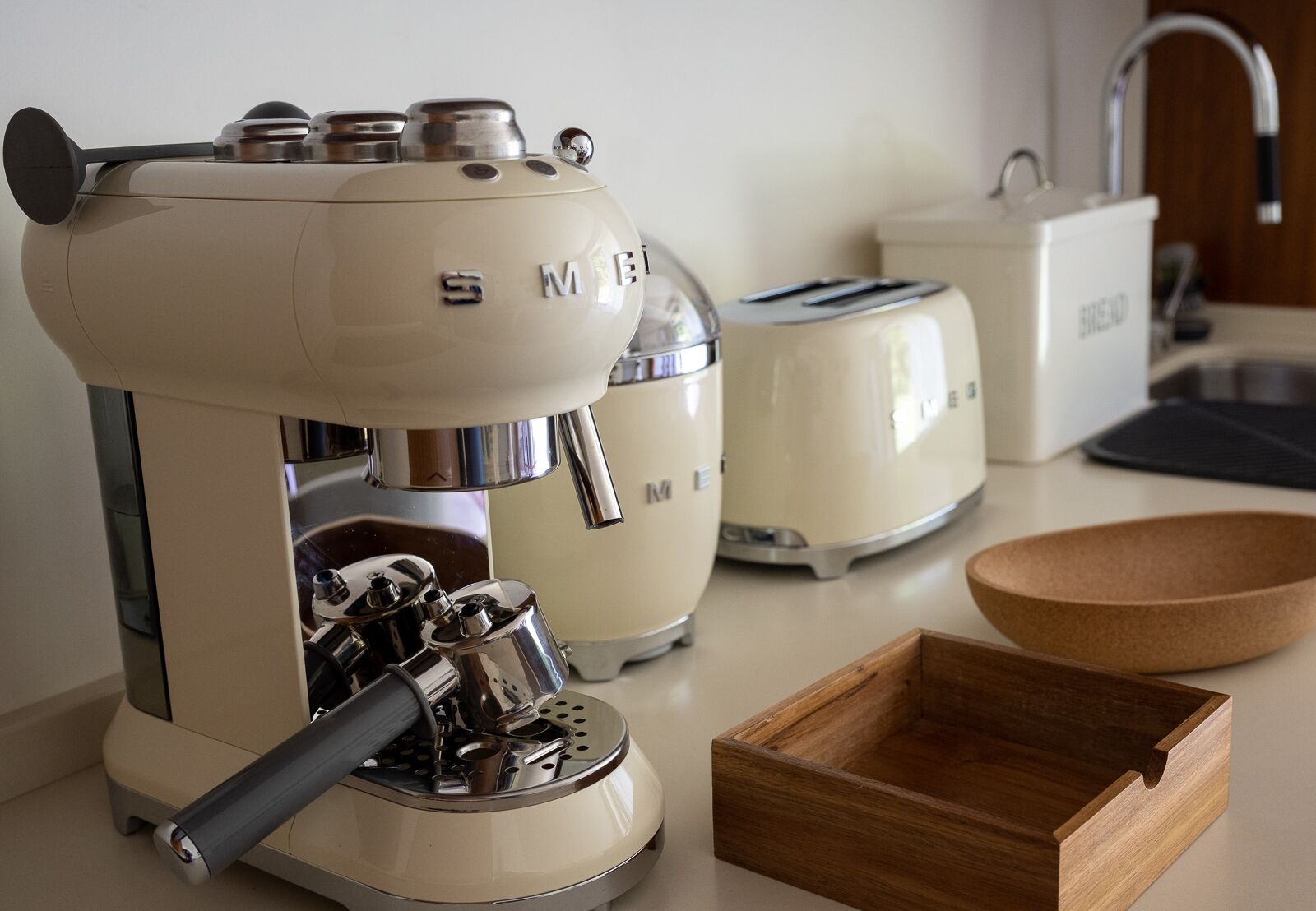 Una cucina con una macchina da caffè, un tostapane e una ciotola di legno sul piano di lavoro.