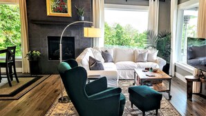 Un salon moderne avec un canapé, des fauteuils, une table basse et une cheminée.