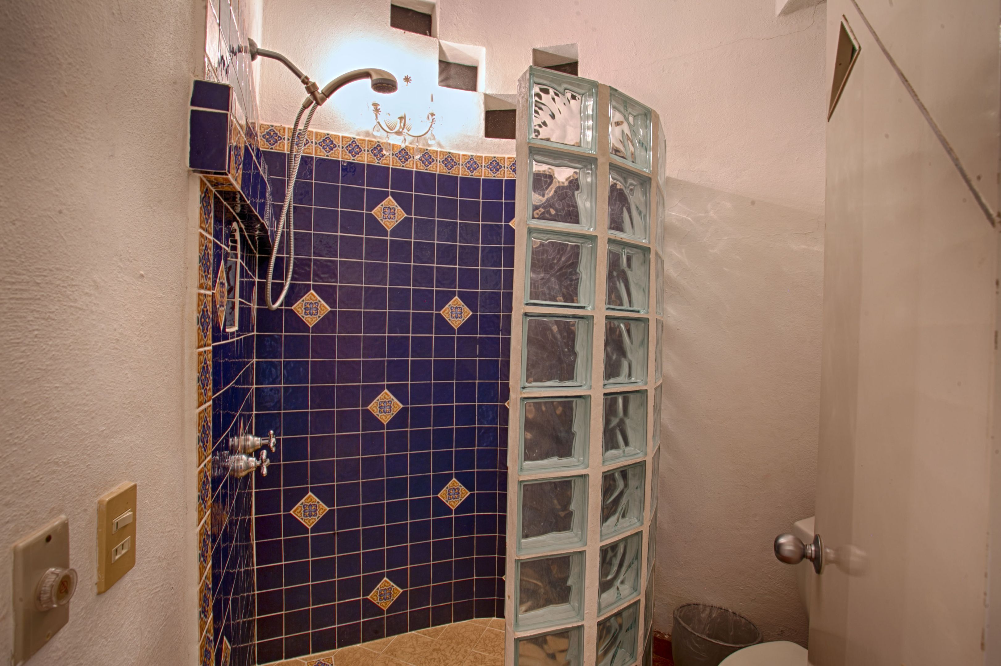 Ein Badezimmer mit blauen Fliesen, einer Duschkabine aus Glas und einer weißen Toilette.