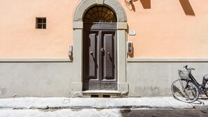 Une façade d’immeuble avec une porte à deux battants, une petite fenêtre et un vélo garé à l’extérieur.