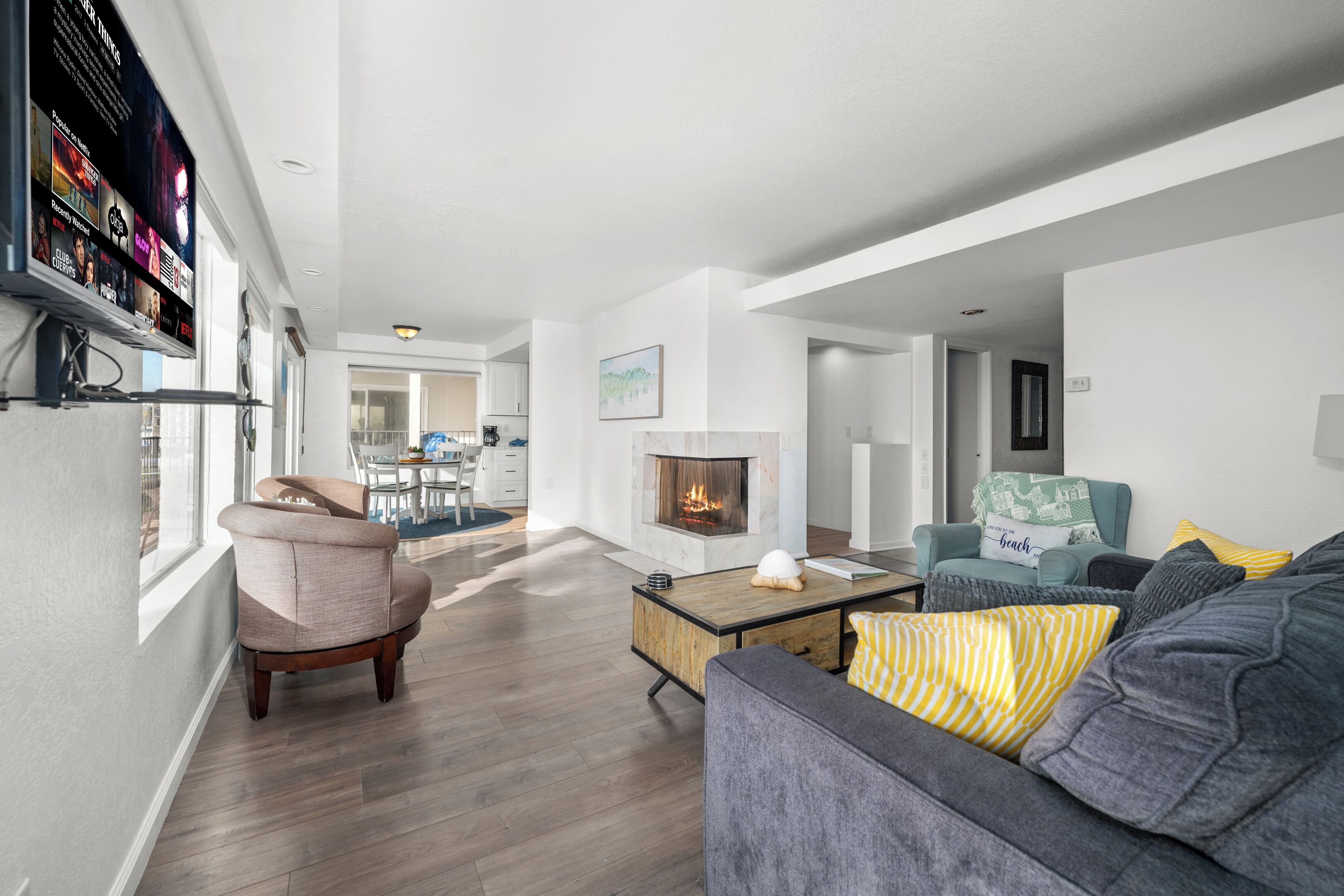 A modern living room with a fireplace, a sofa, a coffee table, and a TV mounted on the wall.