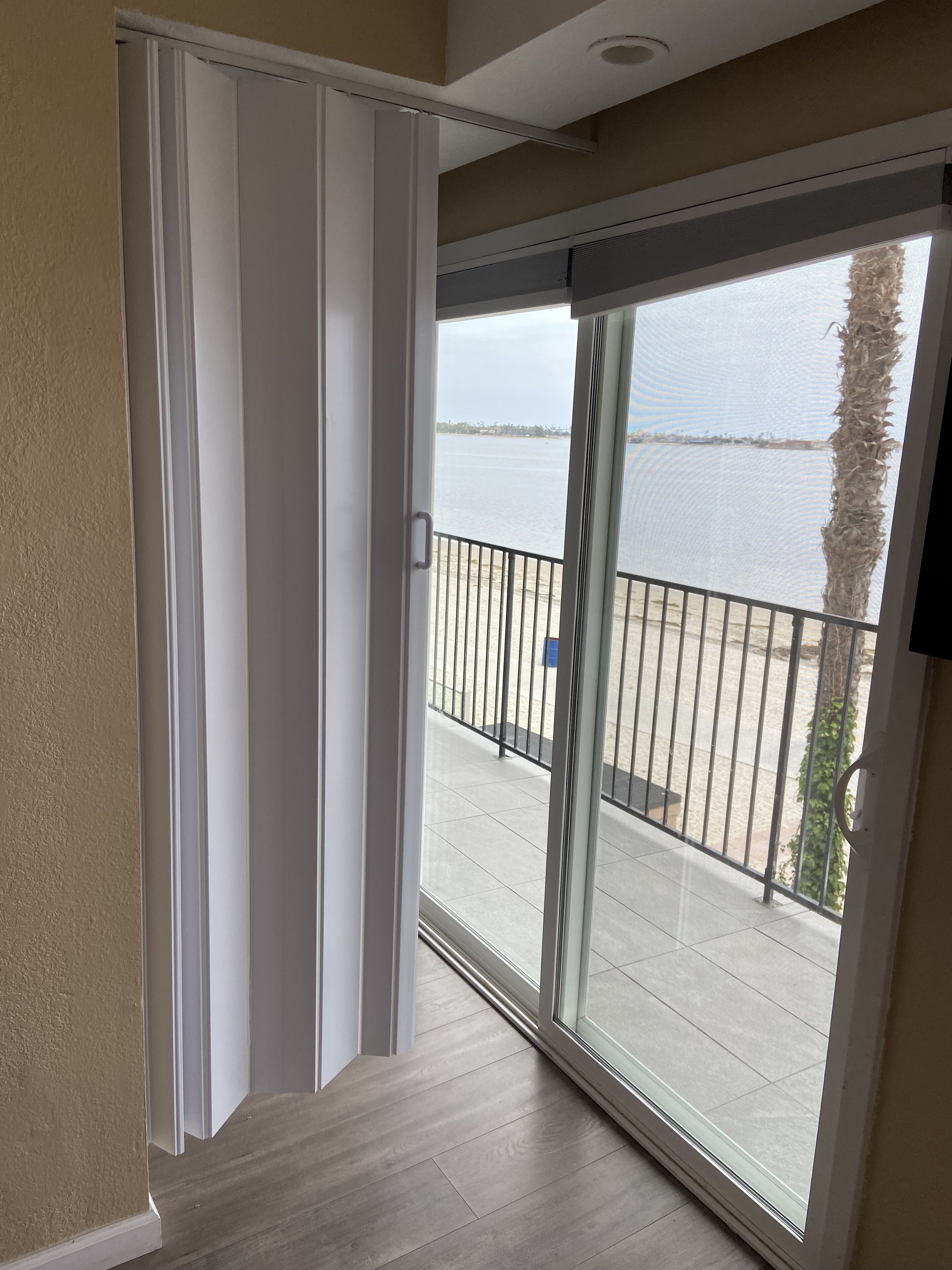 A balcony with a view of a body of water, a railing, and a door leading to an interior space.