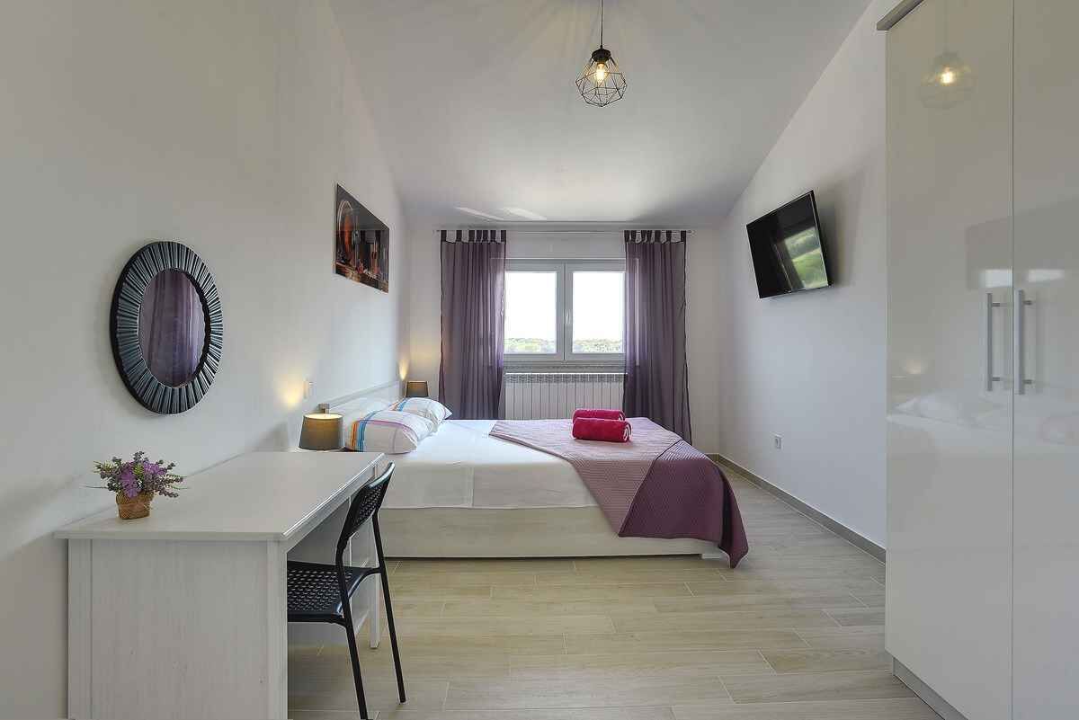 A modern bedroom with a bed, bedside table, and a desk.
