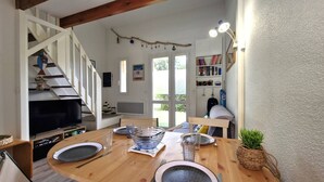 A dining area with a wooden table set for four, a television, and a bookshelf filled with books and decorative items. - Meschers sur Gironde - TOP HOLIDAY VILLA - IDEAL FAMILY RESIDENCE (MESCHERS SUR GIRONDE)