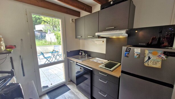 A compact kitchen with a built-in oven, a refrigerator, and a small dining area with a table and chairs. - Meschers sur Gironde - TOP HOLIDAY VILLA - IDEAL FAMILY RESIDENCE (MESCHERS SUR GIRONDE)