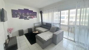 A modern living room with a grey sofa, a black coffee table, and a cityscape artwork on the wall.