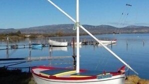 A calm lake with a rowboat docked on the shore, surrounded by calm water and distant mountains.