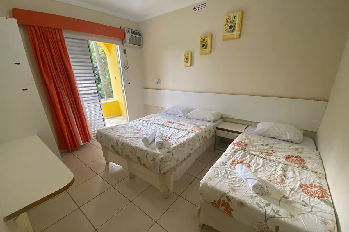 Una habitación de hotel con dos camas, una mesita y una ventana con cortinas.