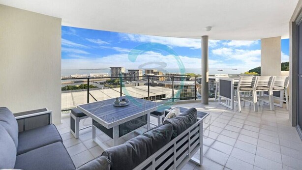 A balcony with a table and chairs, a sofa, and a view of the cityscape. - ZEN AT ARKABA - 3BR Luxury Apartment (Darwin)