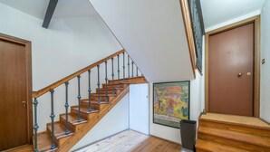 A wooden staircase with black balusters, a wooden door, and a framed map on the wall.