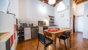 A kitchen with wooden flooring, a dining table with chairs, a microwave, and a sink.