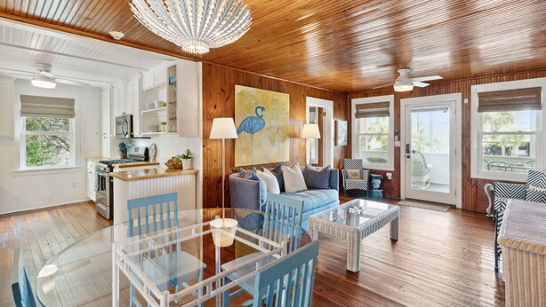 Un salón amplio con techo de madera, una mesa de comedor de cristal y un sofá azul.