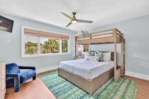 A bedroom with a bunk bed, a desk, a chair, a ceiling fan, and a window with a view of palm trees. - North Beach Cottage! Marsh Views! Screen Porch! Walk to Beach! Amenity access included! (Seabrook Island)