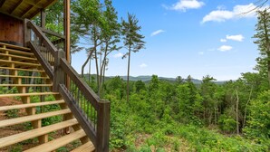 A wooden staircase leading to a cabin with a view of a forest and distant hills. - Romantic retreat with spectacular mountain view. (Blue Ridge)