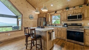 A spacious kitchen with wooden cabinetry, stainless steel appliances, and a large island with bar stools. - Romantic retreat with spectacular mountain view. (Blue Ridge)