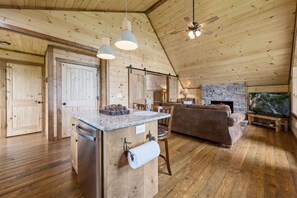 A rustic cabin interior with a kitchen, dining area, and living room.