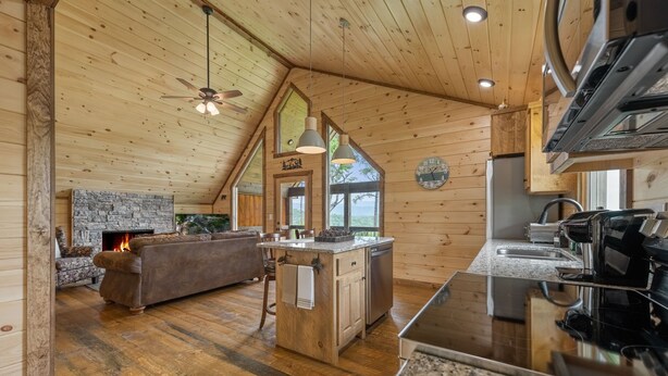 A cozy cabin interior with a stone fireplace, wooden ceiling, and a kitchen area with granite countertops. - Romantic retreat with spectacular mountain view. (Blue Ridge)