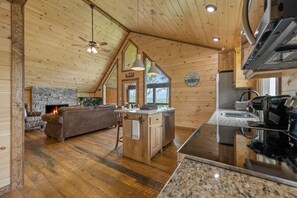 Een gezellig interieur van een chalet met een stenen openhaard, houten plafond en een keuken met granieten aanrechtbladen.