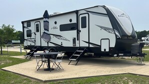 Een camper met een overdekte patio, een tafel en stoelen.