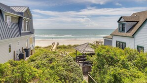 A coastal property with a beach view, a wooden deck, and a gazebo.