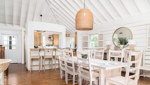A spacious dining area with a long wooden table and chairs, a hanging wicker light fixture, and a large mirror above the table.