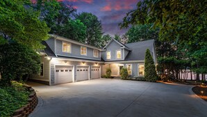 A two-story house with a large garage, surrounded by trees and a well-maintained lawn. - Grand Bay w/Hot Tub, 440' Shoreline & Optional Boat Rental (Mooresville)