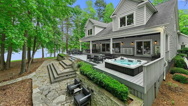 A two-story house with a covered patio, outdoor seating, and a hot tub. - Grand Bay w/Hot Tub, 440' Shoreline & Optional Boat Rental (Mooresville)