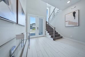 A modern interior with a staircase, a door leading outside, and artwork on the walls.