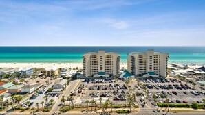 Un hôtel situé en bord de mer, avec plusieurs étages, un parking et une vue sur l’océan.