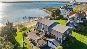 A coastal house with a dock, a garage, and a well-maintained lawn. - Cape Cod Waterfront with Stunning Views (Buzzards Bay)