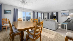 A room with a dining table, chairs, a sofa, a TV, and a ceiling fan. - Cape Cod Waterfront with Stunning Views (Buzzards Bay)