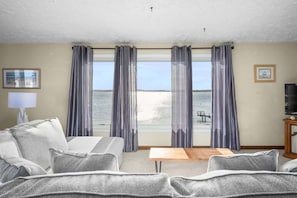 Une pièce avec vue sur la mer, un canapé, une table et un téléviseur.