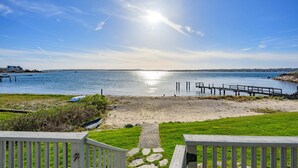 A beach with a wooden deck, a stone pathway, and a view of the water. - Cape Cod Waterfront with Stunning Views (Buzzards Bay)