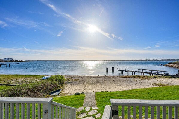 Une plage avec une terrasse en bois, un sentier en pierre et une vue sur l’eau.
