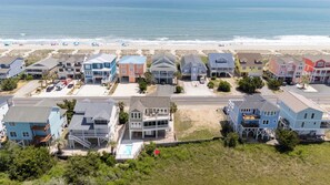 A coastal residential area with houses directly adjacent to the beach, featuring a mix of single and multi-story buildings with balconies.