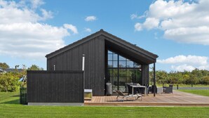 Een modern gebouw met een groot raam en een houten terras.