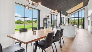 Een moderne keuken met een groot eiland, veel natuurlijk licht en uitzicht op de omgeving.