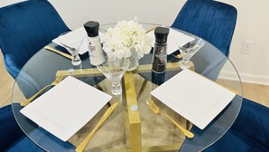 Une table ronde en verre agrémentée de détails dorés, entourée de chaises bleues.